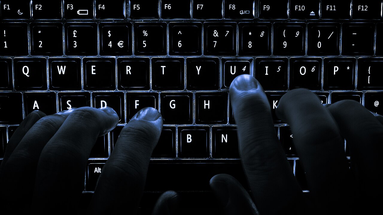 Un clavier d’ordinateur portable rétroéclairé, la plupart des doigts posés sur la rangée de repos, la touche U enfoncée
